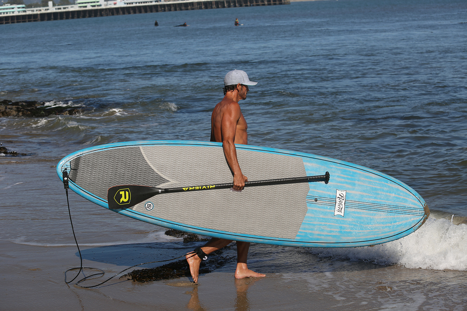 image of man carrying a paddleboard into the surf.